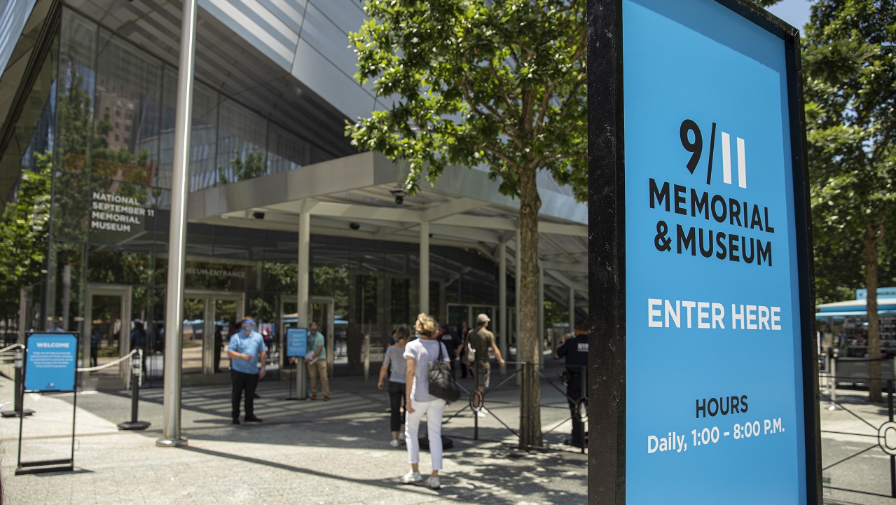 Patrons gather in PPE to enter the reopened 9/11 Memorial on a summer day.