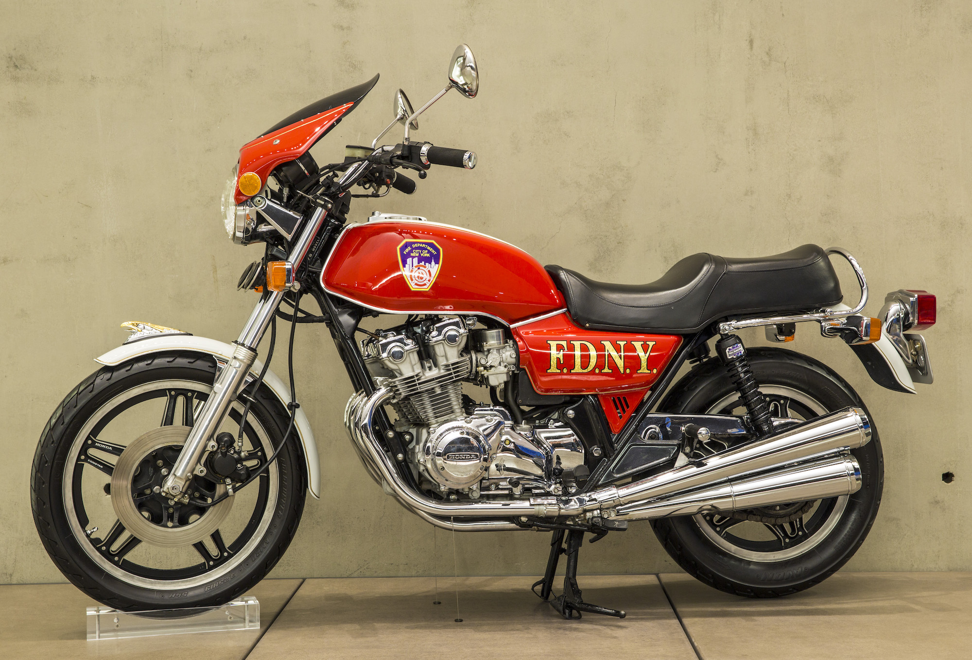 A fire engine-red motorcycle against a beige backdrop