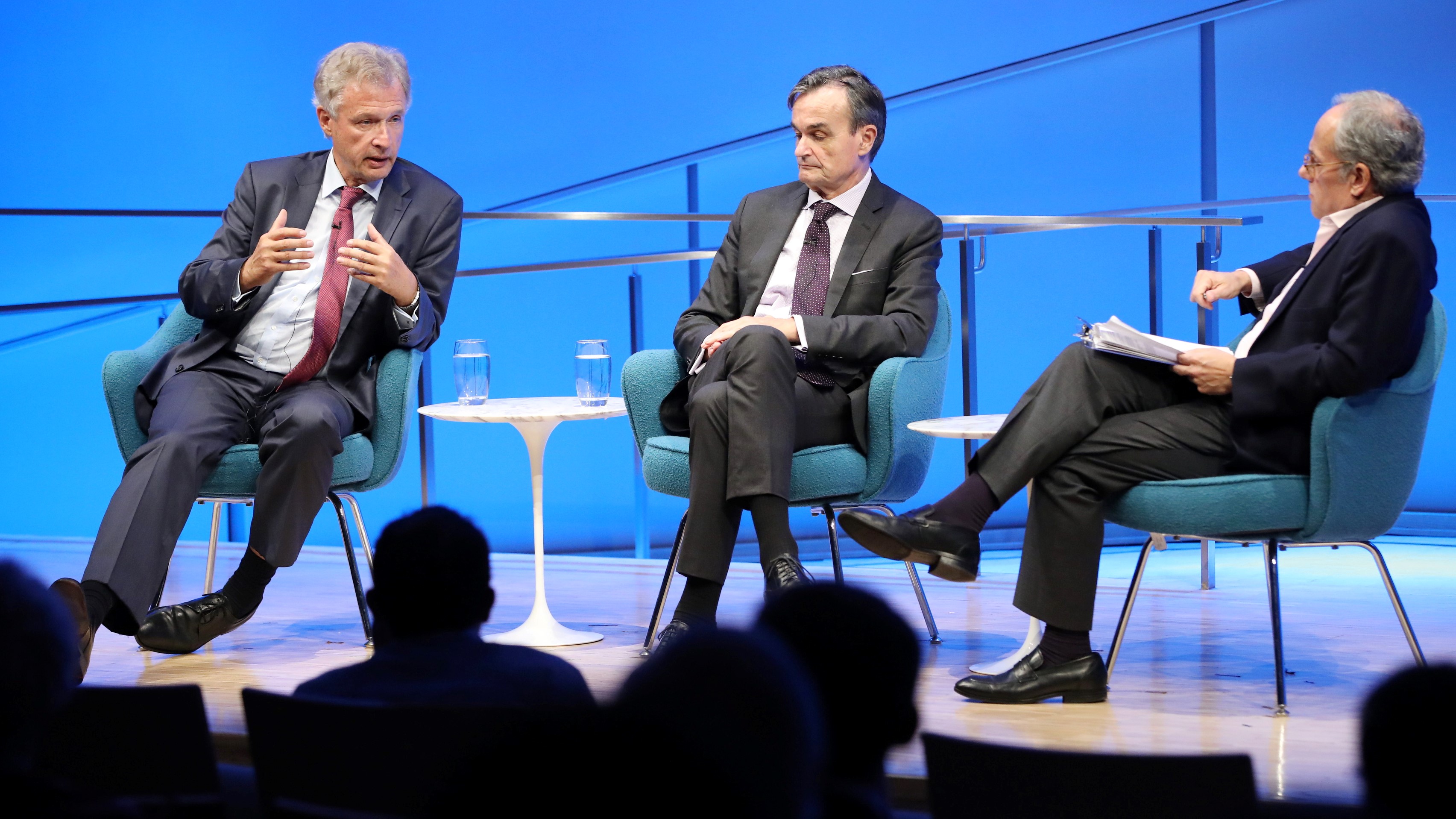 The silhouettes of audience members are visible in the foreground as Peter Ammon, former Ambassador of Germany to the U.S., speaks onstage during a public program in the Museum auditorium. He is seated next to Gérard Araud, former Ambassador of France to the U.S., and Clifford Chanin, the executive vice president and deputy director for museum programs.