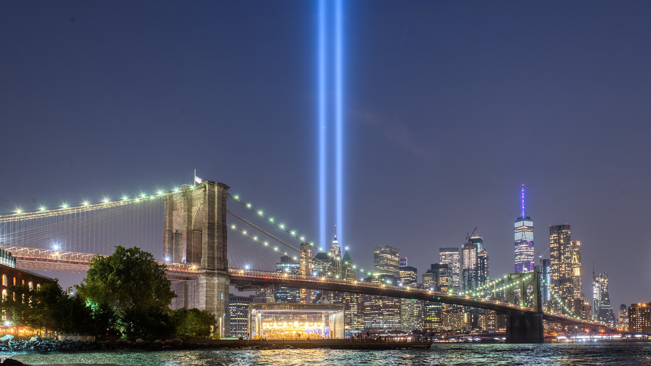 Beams of blue light against nighttime sky and Brooklyn Bridge