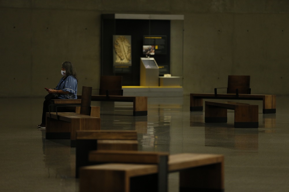 A family member, wearing a mask, sits inside the newly reopened 9/11 Memorial Museum.