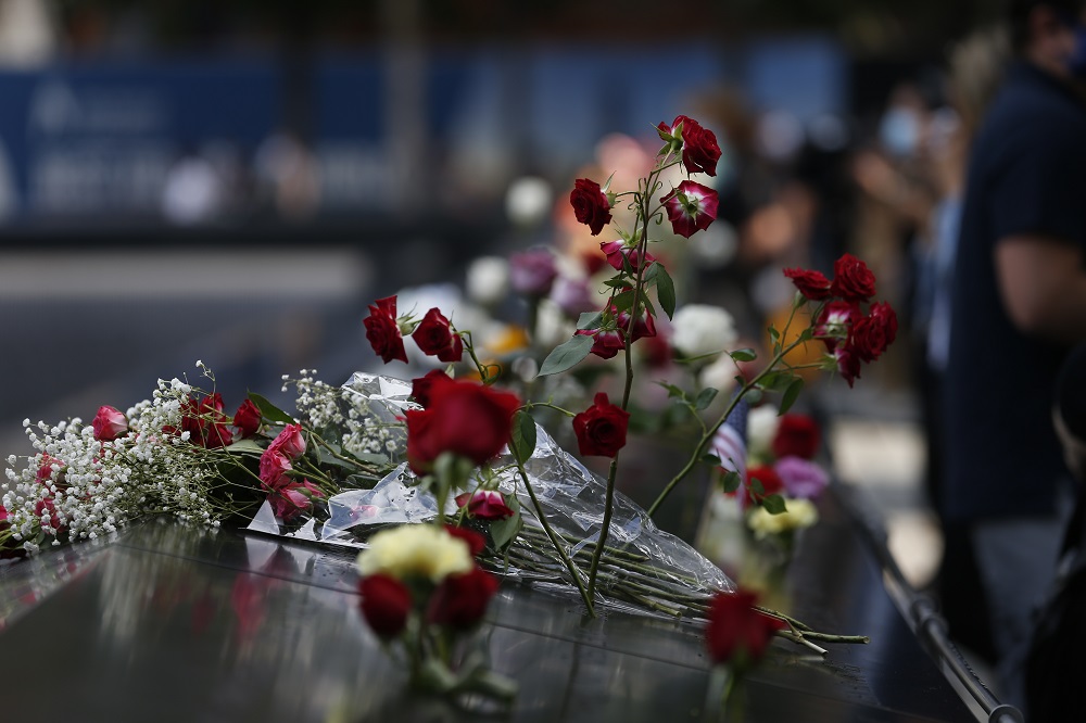 Long stemmed red roses are left on the memorial parapet.