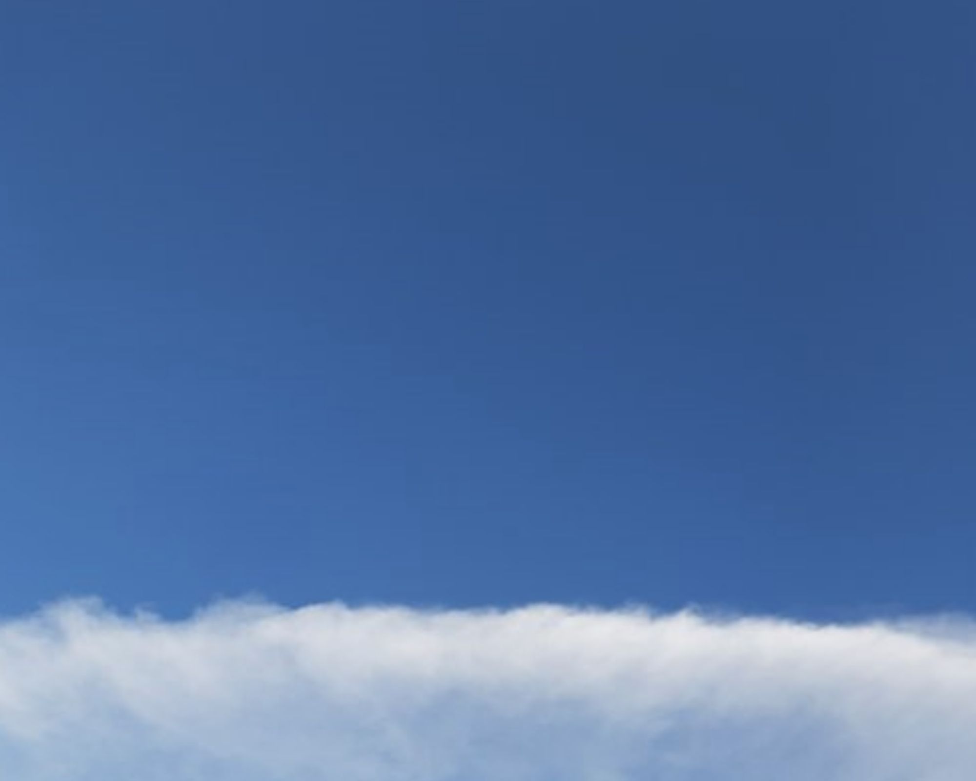 Blue sky over single layer of cloud fluff