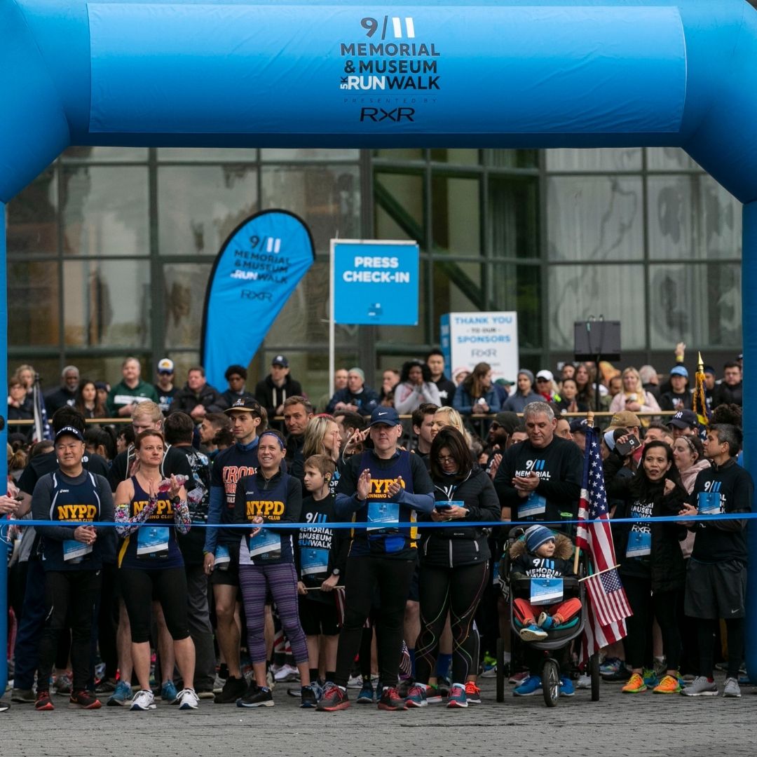 A group of participants in blue t-shirts pose under an inflated blue arch