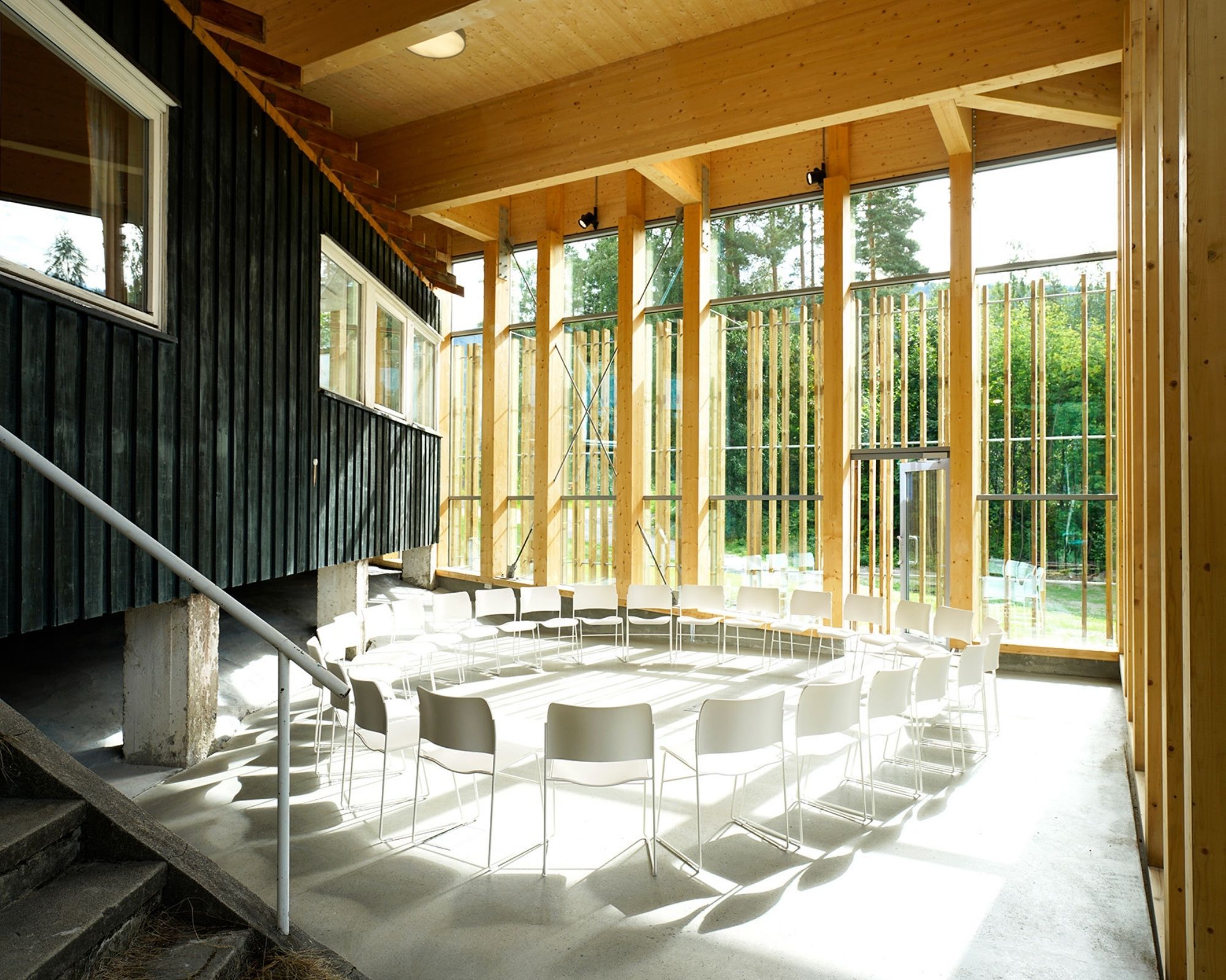 A circle of white folding chairs in front of a ceiling to floor window