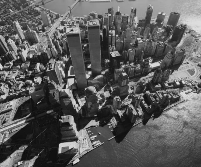 Aerial view of lower Manhattan with Twin Towers on a sunny day. The black and white image has a fishbowl effect. 