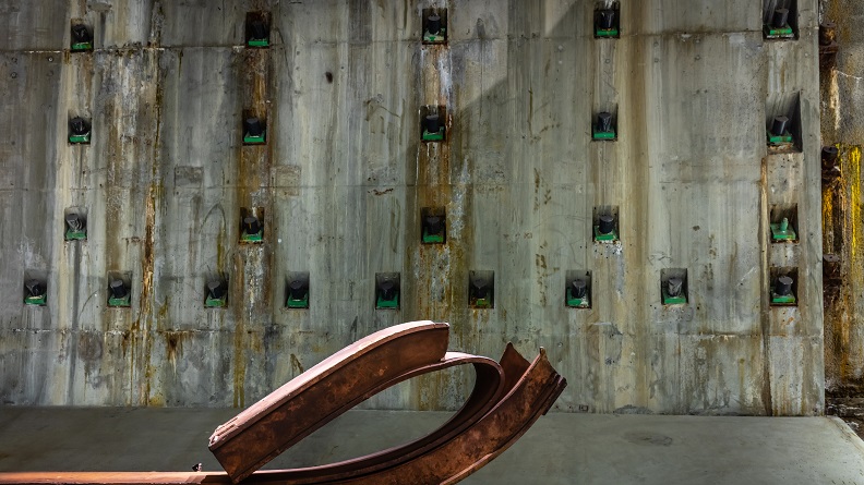 The slurry wall in the Museum's Foundation Hall with a curved, rusted piece of impact steel in the foreground. 