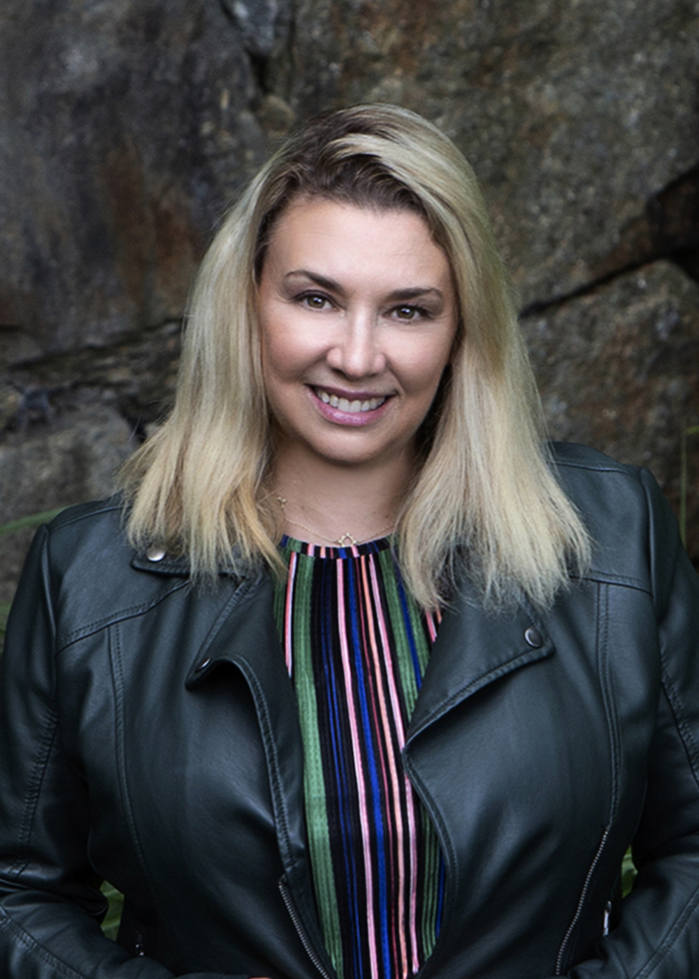 A smiling blonde woman in a black leather jacket