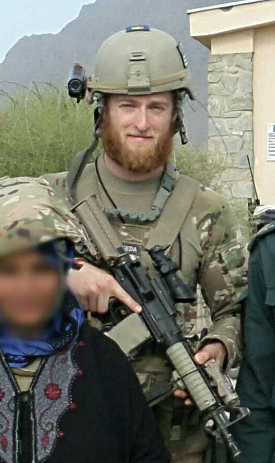 Visionary Phil Caruso in uniform, holding a rifle