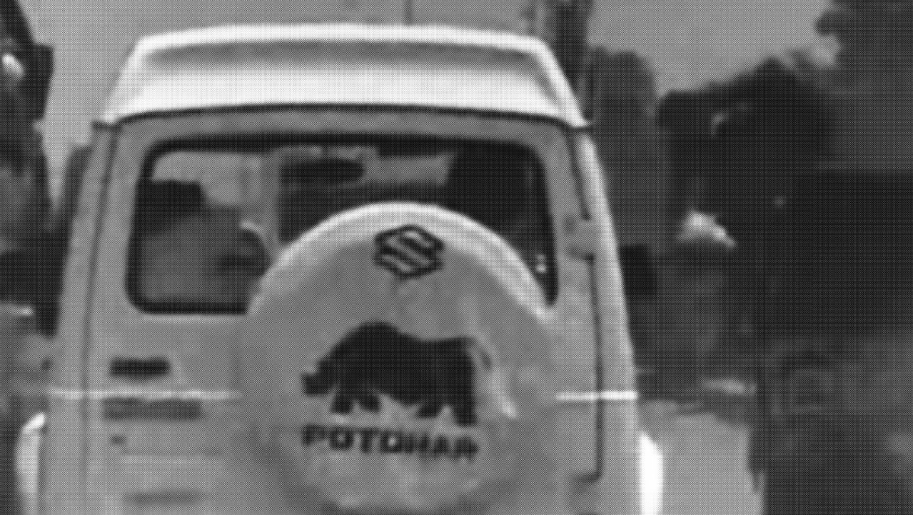 Still from video of the back of a white van with animal logo on the back on the road.