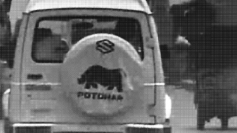 Still from video of the back of a white van with animal logo on the back on the road.