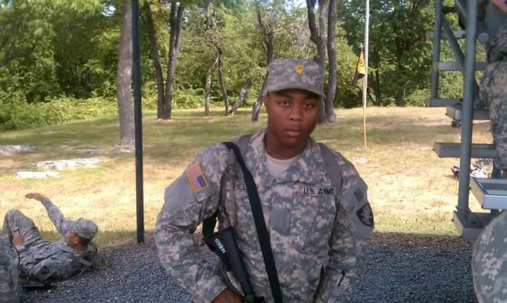 A soldier stands in a training camp environment in his fatigues.